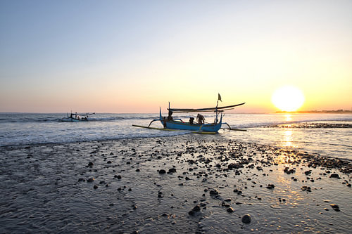 Een jukung-vissersboot aan de kust bij zonsondergang in Medewi, Bali