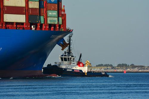 Sleepboot Brent bij de boeg van een Containerschip