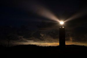 Lighthouse in the dunes with lightbeams at night