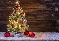 Besneeuwde kerstboom met lichtjes, rode kerstballen, dennenappel, sneeuw en decoratie in de vorm van
