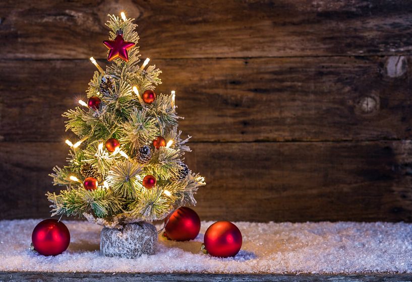 Besneeuwde kerstboom met lichtjes, rode kerstballen, dennenappel, sneeuw en decoratie in de vorm van van Alex Winter