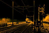 A typical Dutch train comes out of the fog and passes a railway crossing