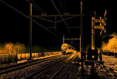 Ein typischer Niederländischer Zug kommt aus dem Nebel und passiert ein Bahnübergang