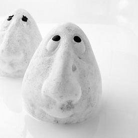 Photo noir et blanc de deux têtes en céramique caractéristiques debout dans un lac blanc. sur Hans Post