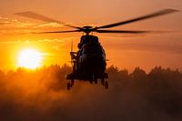 Een Cougar transporthelikopter doet stof opwaaien tijdens zonsondergang