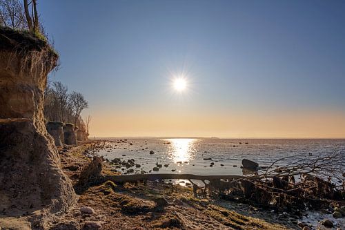 Avondzon met in het water gereflecteerde stralen bij de steile kustklif van het Duitse eiland Poel i