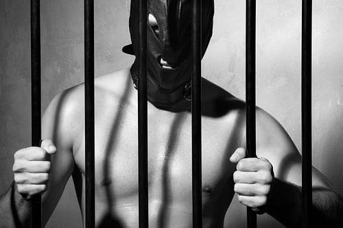 Man achter gevangenis tralies in onderdanige fetisj stijl