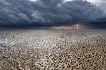 Waddenzee bij laag water met onweerin de verte.