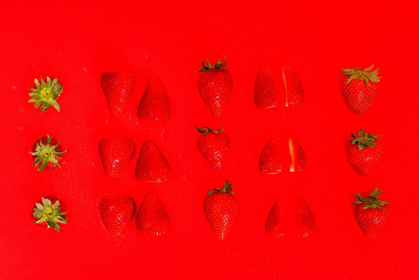 Sliced strawberries on red background by Wim Stolwerk