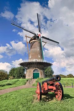 Traditionelle holländische Windmühle auf mit einem alten roten Kanon vor