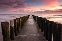 Paalhoofden op het strand tijdens zonsondergang