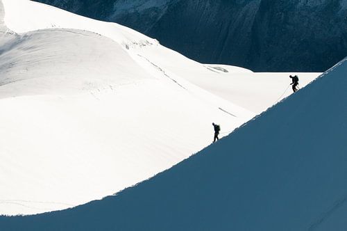Alpinists descend a snow bridge