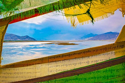Paysage de montagne au Tibet, vu à travers des drapeaux de prière