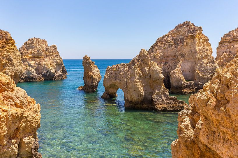 Rocks in shallow blue sea on the Portuguese coast by Ben Schonewille
