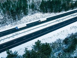 Highway through a snowy forest landscape seen from above