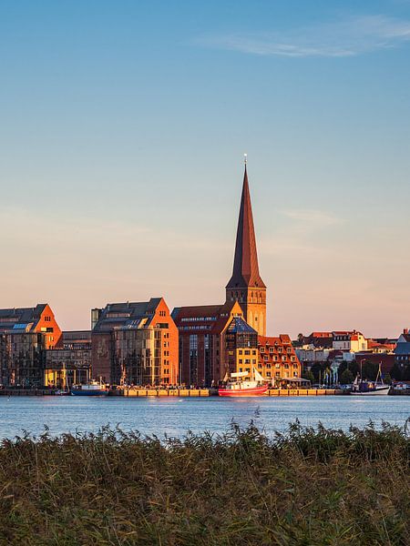 Uitzicht over de Warnow naar de Hanzestad Rostock in de avond van Rico Ködder