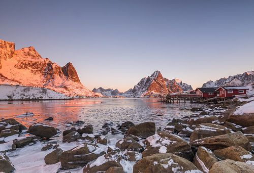 Schneebedeckte Berge und gefrorener Fjord im morgendlichen Sonnenlicht in Reine auf den Lofoten in N