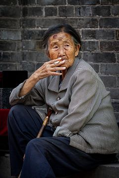 Oude Chinese vrouw die een sigaret rookt van Roland Brack