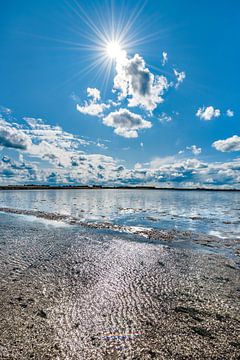 Wolkenlucht boven een spiegelend wateroppervlak van de Waddenzee