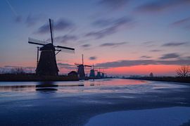 The windmills at Kinderdijk before sunrise with orange-blue sky by Thom Vermeulen