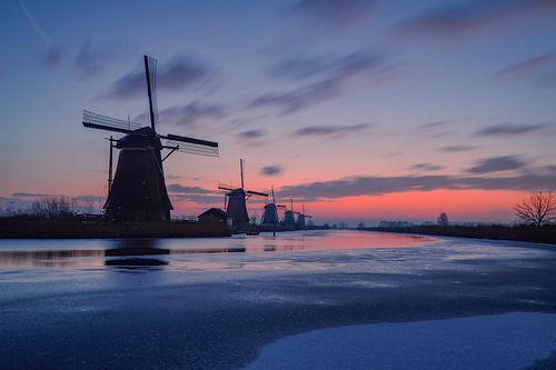 De molens bij Kinderdijk voor zonsopkomst met oranje-blauwe lucht
