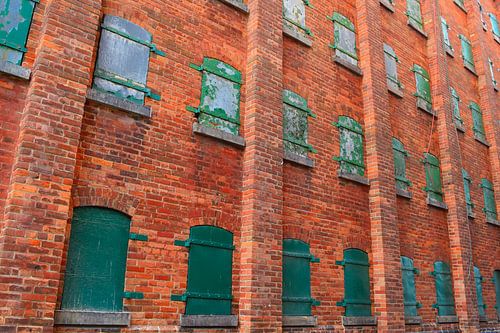 Industriewand mit orangefarbenem Ziegelstein und grünen Fensterläden