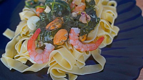Fettuccini met spinazie en kaas roomsaus en zeevruchten geserveerd op een bord