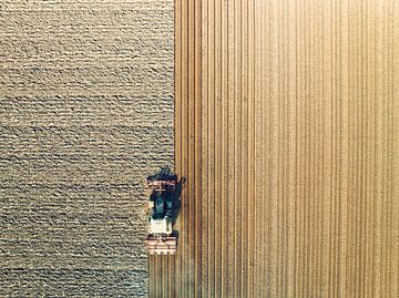 Tractor maakt de grond klaar voor het planten van gewassen van bovenaf gezien