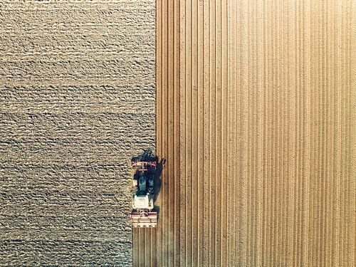Tractor maakt de grond klaar voor het planten van gewassen van bovenaf gezien