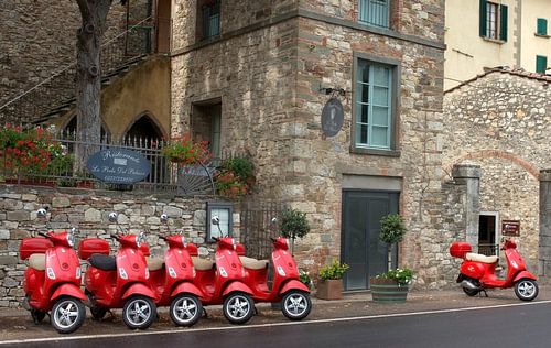 Red Vespa scooters in an Italian street.