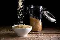 rice grains falling into a white bowl beside a glass jar with rice on a rustic wooden table against  by Maren Winter thumbnail