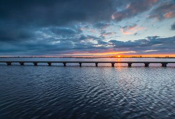 Landschap, wandelpad over het water bij ondergaande zon van Marcel Kerdijk