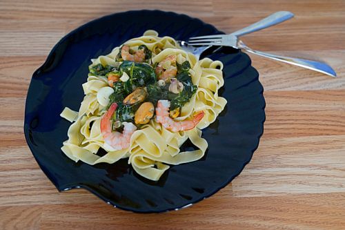 Fettuccini met spinazie en kaas roomsaus en zeevruchten geserveerd op een bord