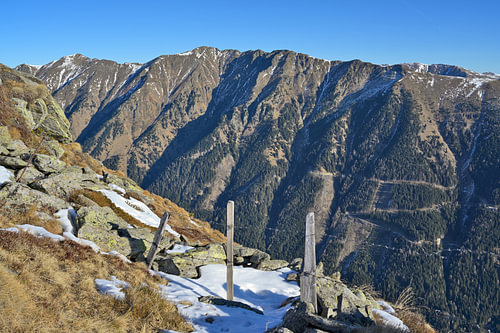 Bergkette mit Wäldern und vereinzelten Schneefeldern