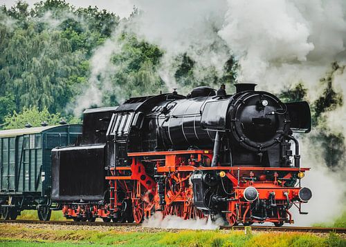 Oude stoomtrein rijdend door het platteland met goederenwagons