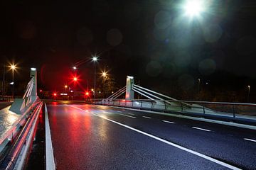 Brug met drukke straat en verkeerslichten 's nachts