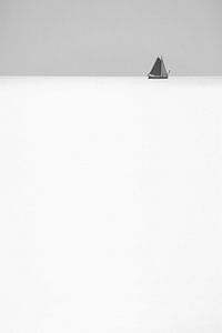 Zwart-wit abstracte foto van een zeilschip aan de horizon op zee van Bas Meelker