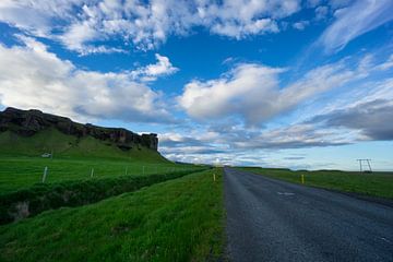 IJsland - Blauwe lucht boven de weg tussen groene weide en vulkanische rotsen bij zonsopgang van adventure-photos