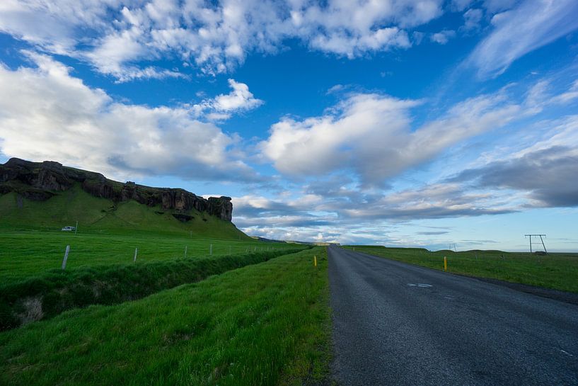 Iceland - Blue sky over road between green meadow and volcanic rocks at dawn by adventure-photos