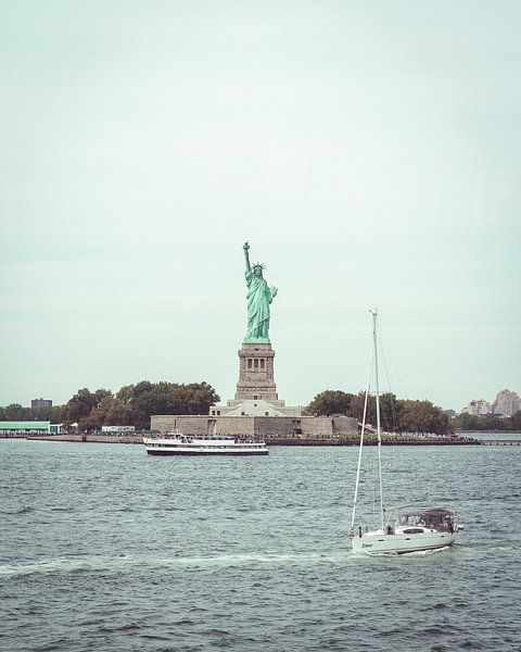 Statue of Liberty is passed by sailboat by Mick van Hesteren