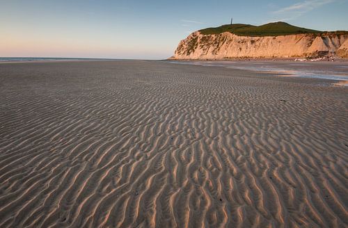 Ribbels in het zand met krijtrotsen op de achtergrond bij ondergaande zon