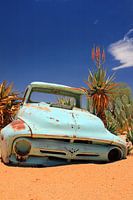 Old rusted and abandoned vintage car wreck in the sand