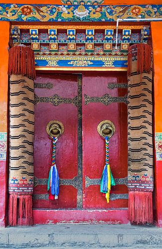 Rode deur met gebedsvlaggen in een Tibetaans klooster
