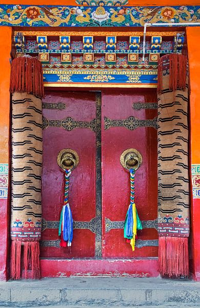 Rode deur met gebedsvlaggen in een Tibetaans klooster van Rietje Bulthuis