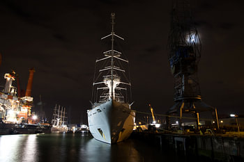 Front view of a big sail cruise ship laying in the harbour at night.
