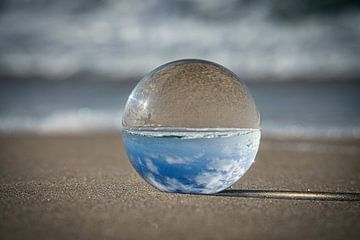 View through the glass ball on the beach. Sea and sky in the background. by Martin Köbsch