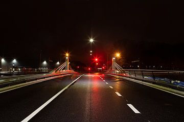Brug met drukke straat en verkeerslichten 's nachts