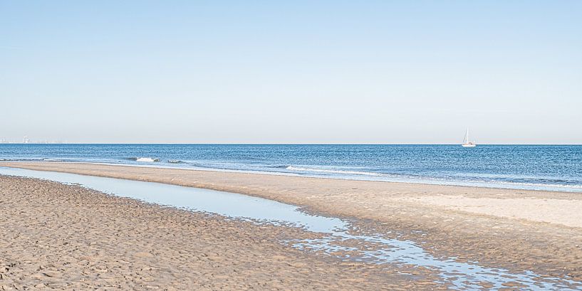 Het Scheveningse strand en zee met een zeilboot. van MICHEL WETTSTEIN