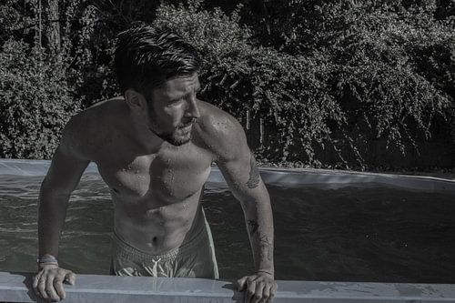 Man met onbloot torso komt sexy uit zwembad in zwartwit