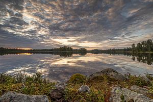 Steine und Heidekraut an einem spiegelglatten schwedischen See unter einer imposanten Wolkendecke